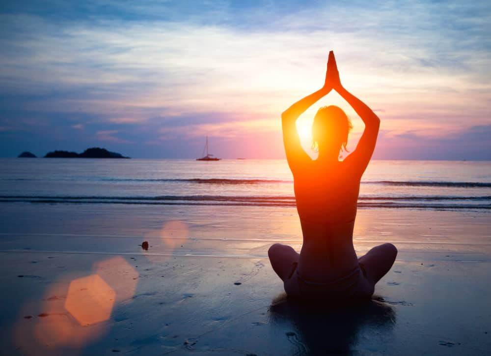 woman doing yoga on beach with new thought mind science focus