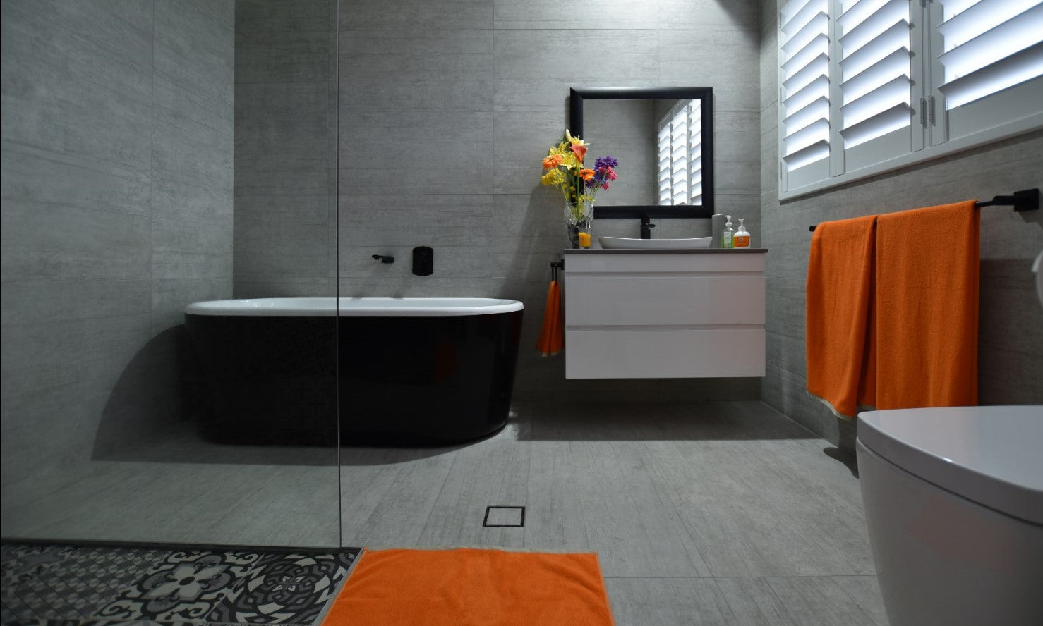 Bathroom uses large format tiles, wall hung vanity and a walk in shower for low maintenance cleaning design