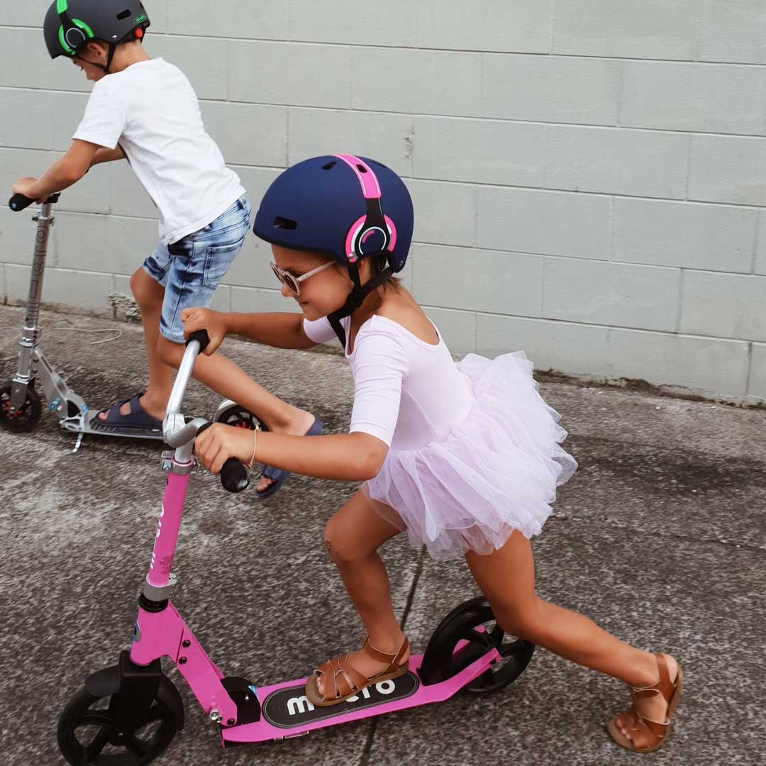 brother and sister on their 2 wheel scooters going to school