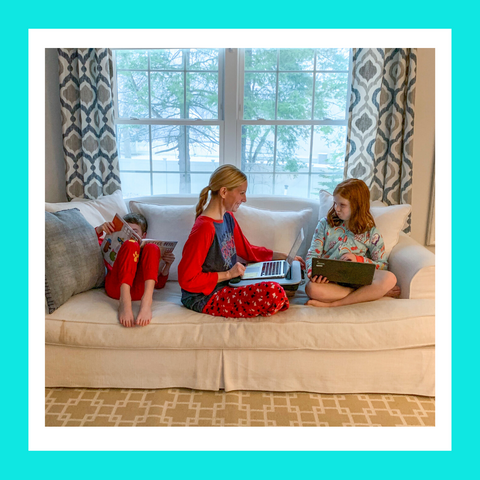 Woman working with a laptop sitting on a couch with her son and daughter