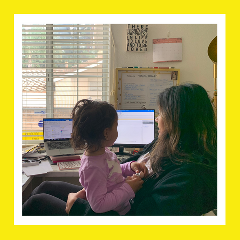 Woman sitting at a desk with her daughter while working