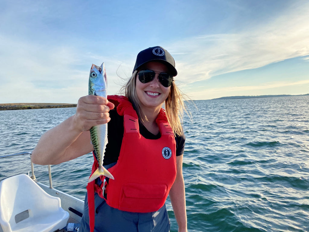 woman in red life vest holding up mackerel that she caught