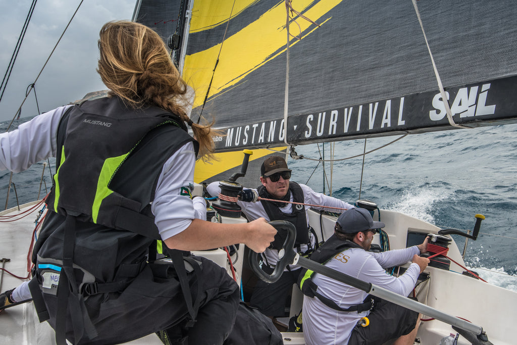 back of young women at helm of ocean racing yacht at full sail 