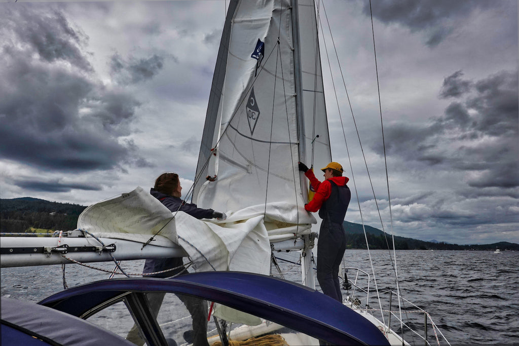 sail being pulled down with cloudy skies of Vancouvers west coast behind