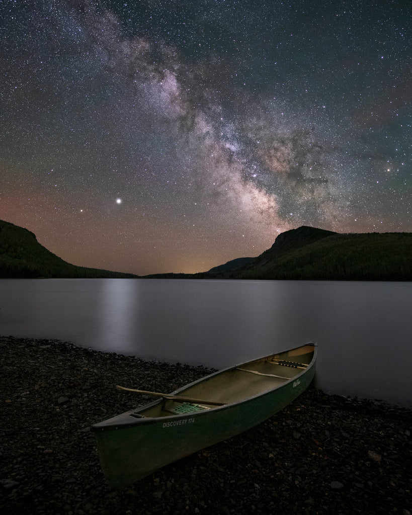 canoe on shore under starry moonlight sky 
