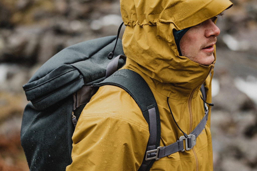 Man walking on a soaking wet day with yellow jacket and grey backpack