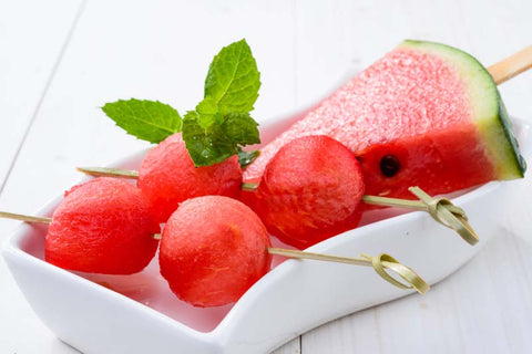 Watermelon balls on a kebab stick in a small bowl