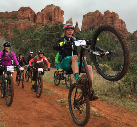 Group of women trail riding with the lead one doing a wheelie