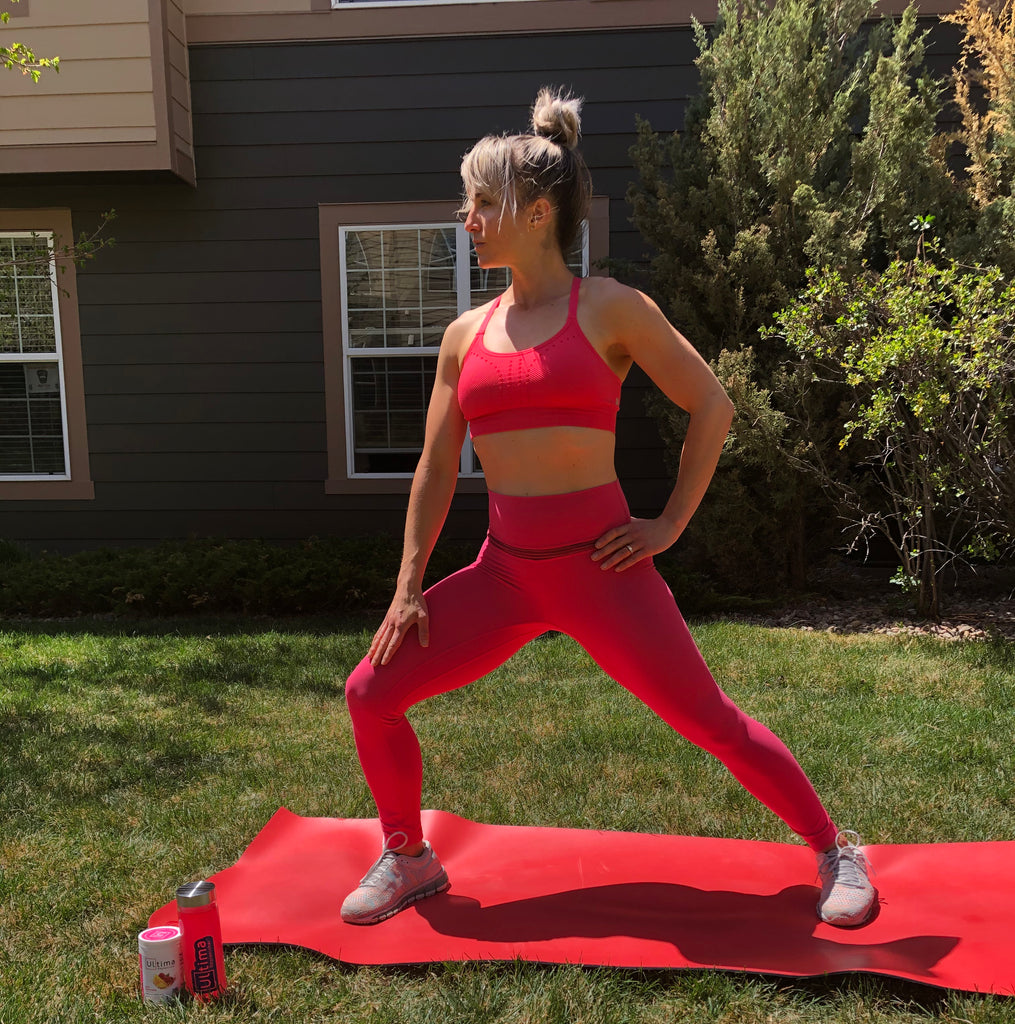 Woman in yoga gear stretching outside and staying hydrated with Ultima Replenisher