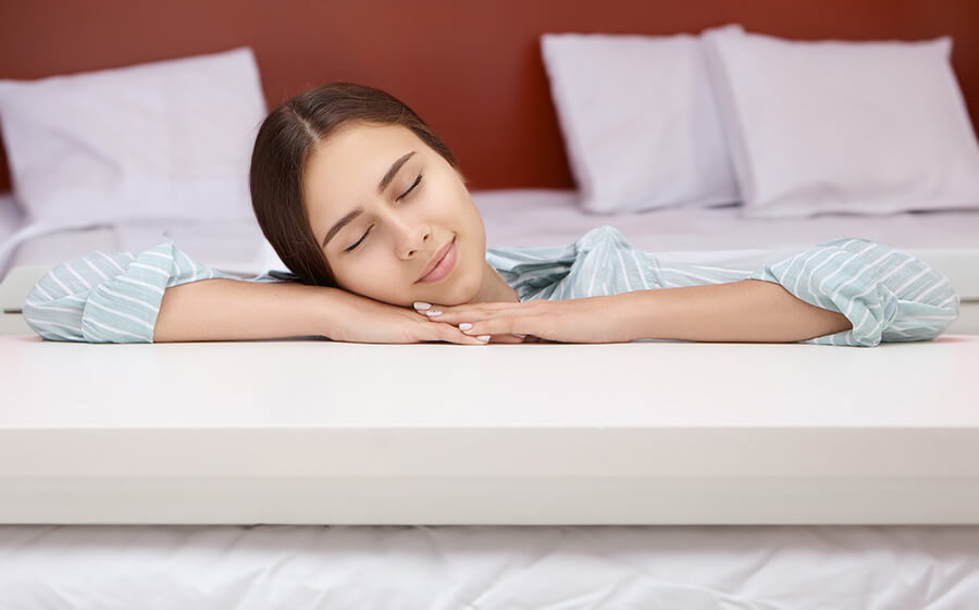 Person placing their head on our mattress topper, with closed eyes, and feeling the texture