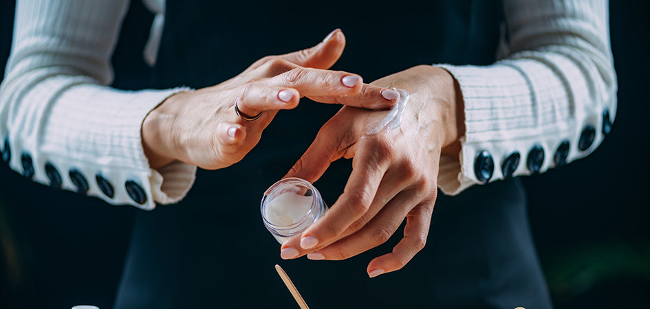 Woman rubbing cbd lotion on her wrist for pain relief.