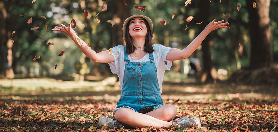 woman playing with leaves outside. pure hemp cbd oil for sale.