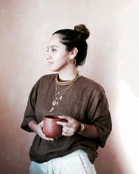 Woman holding red coffee mug while wearing DYLAN LEX jewelry