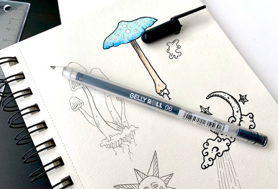 Sakura Gelly Roll pen on top of sketchbook with doodles Andie Laf Designs