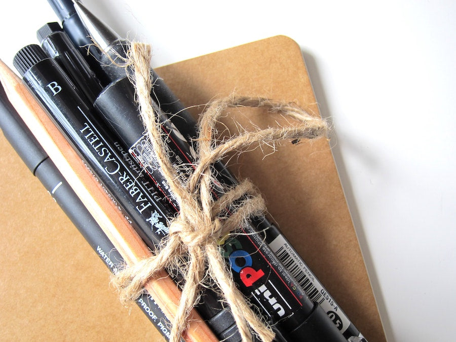 close up of bundle of black pens tied up with twine on a journal