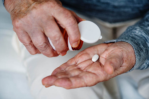 Weathered, aging hands pouring out hydrocodone