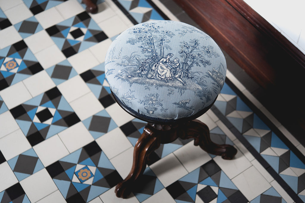 French Provincial stool sitting atop a tessellated tile floor