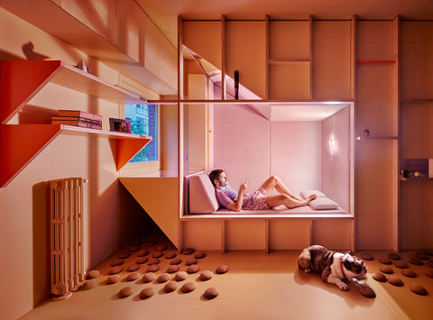 Man relaxing in bed under warm lighting while dog sits on the floor