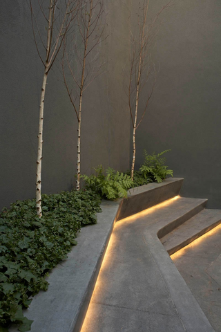 Outdoor grey concrete stairs with LED strip lighting sitting underneath each stair and illuminating the stair