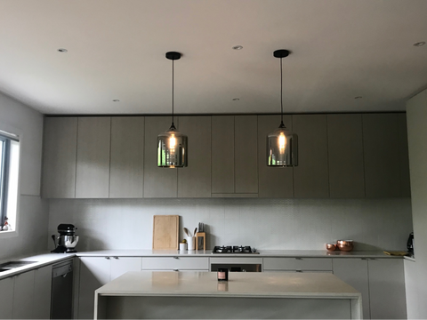 Minimal kitchen with two silver pendant lights hanging above kitchen island