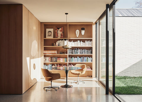 Stylish room with table, chairs, bookshelf and large window.