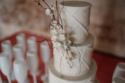 Modern wedding cake with sugar flowers surrounded by white champagne glasses in Cheshire.