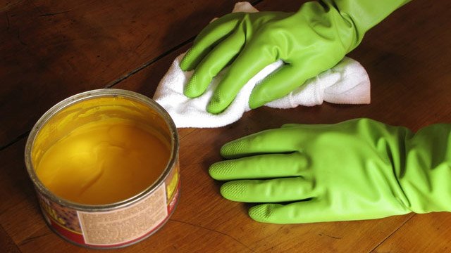 person using furniture wax on wooden table