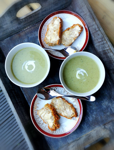 Wooden tray with two bowls of soup and two plates with slices of Cheese n' Onion bread with butter