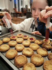 Children adding jam to Christmas biscuits