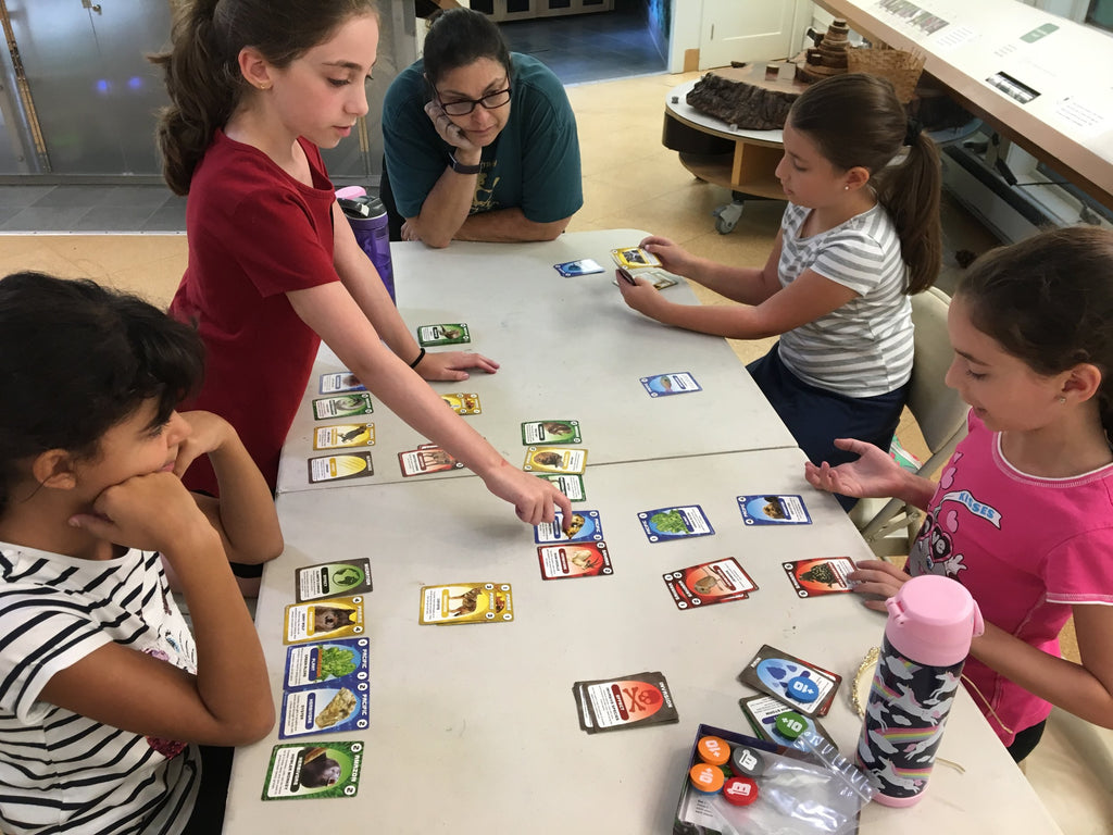 Teacher educator Rycki Waldeck watches as campers discuss their strategy for building biomes.