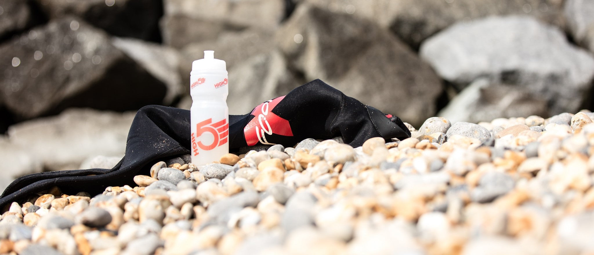 Water bottle and wetsuit on a beach