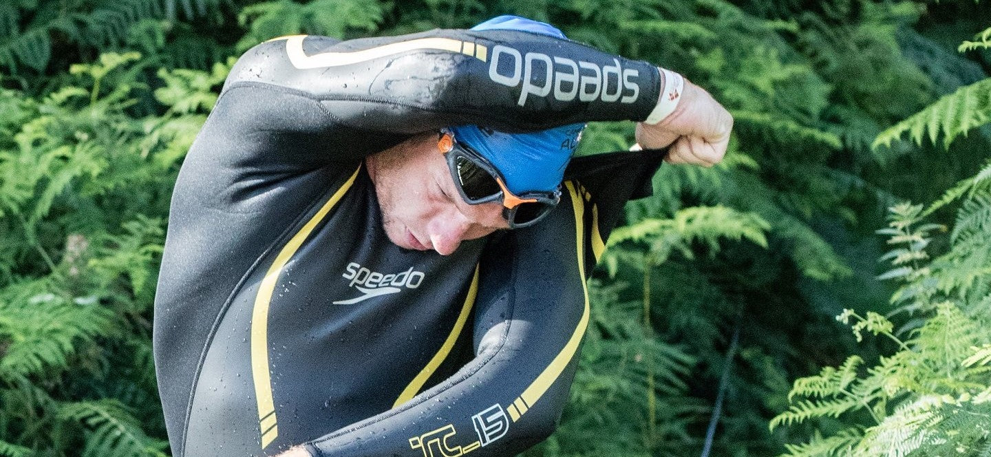 Man removing a wetsuit during a triathlon