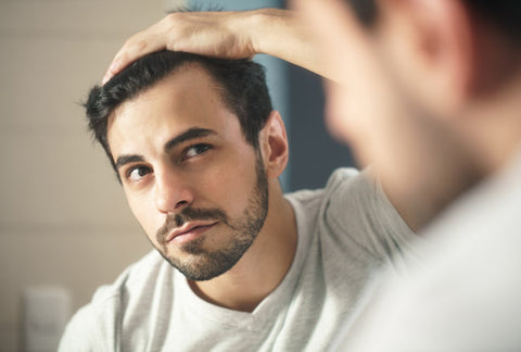 Man with full of hair staring at himself through the mirror