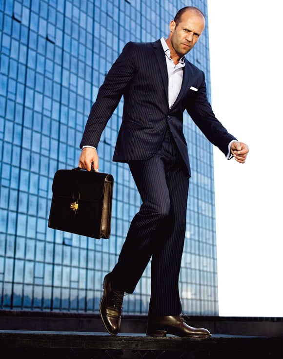 jason statham in formal wear with a case in his hand 