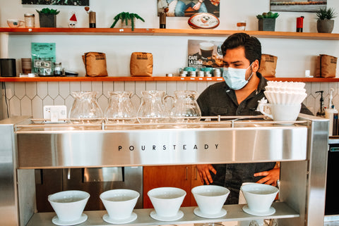 Barista looking at pourover machine.