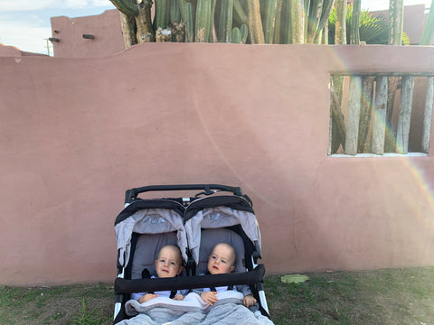 Twin babies smiling in Mountain Buggy duet in silver