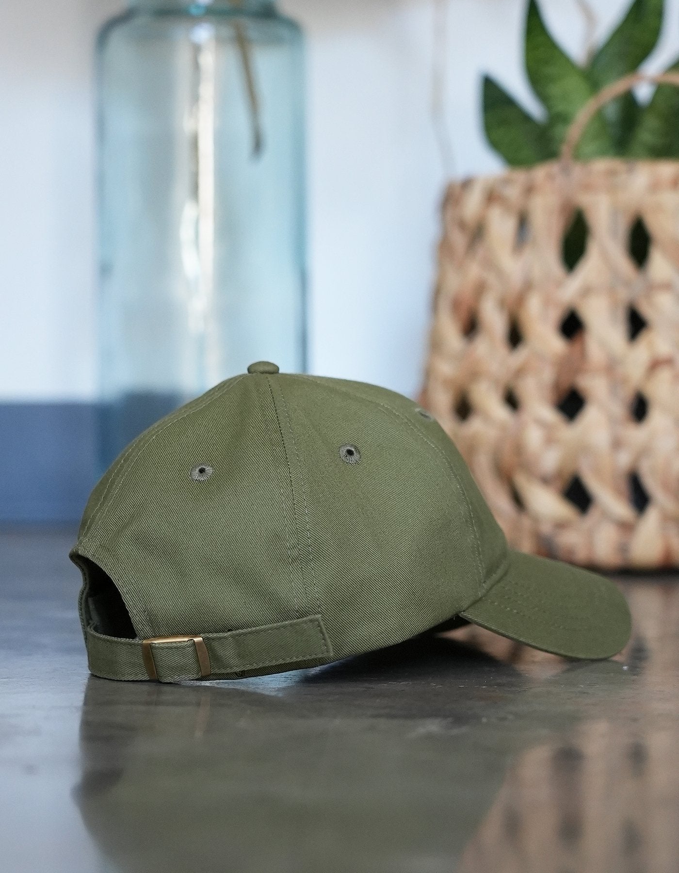 Crimson tavernorlando aloha dad hat in the color olive green. Showcasing the back and the beautiful bronze hardware on the adjustable strap