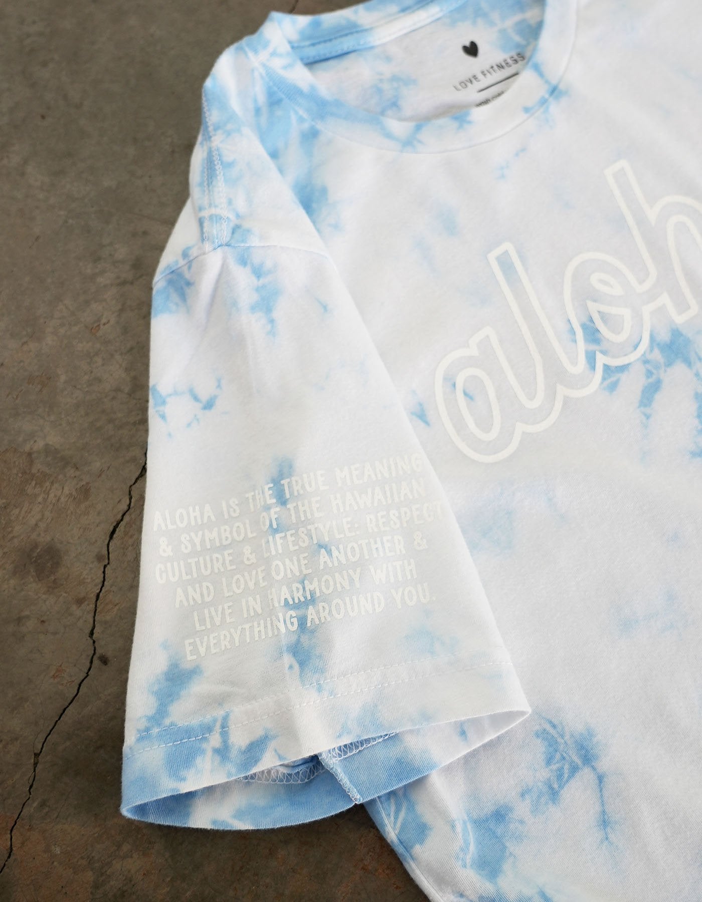Love fitness aloha every day sky blue tie dye tee and up close picture of the right sleeve with the aloha meaning mantra