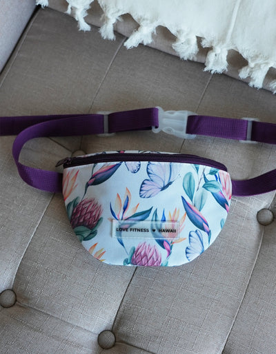 Crimson tavernorlando Island Dreams Fanny Pack with an all over print with island flowers and butterflies. Straps in a dark purple and compartment that fits all the on the go essentials