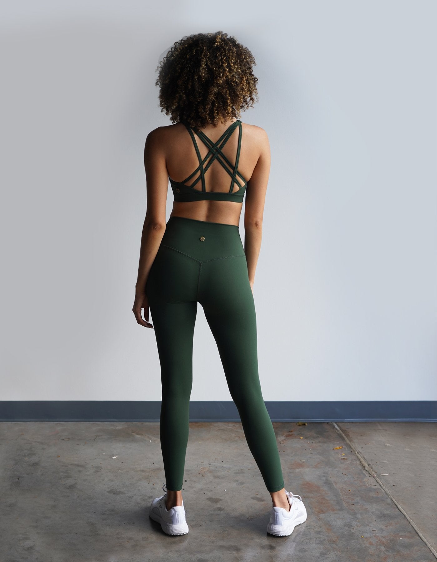 Crimson tavernorlando model showing the back detailing of the Leilani Sports bra and Essential Leggings in the beautiful color Eden