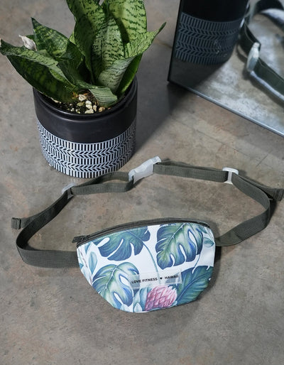 Crimson tavernorlando fanny pack in a beautiful monstera print with a silicone clear label that says love fitness hawaii.b=