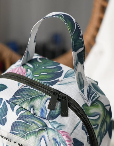 Up close picture of the Crimson tavernorlando Monsteral Mini Back Pack with all over Monstera Print and the dark olive green zipper and zipper pulls with heart logos. Oversized hand for easy carry