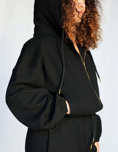 Crimson tavernorlando Phaedra Jacket in the color black. Waffle texture with a zipper, oversized hood and drawstrings on the side to adjust