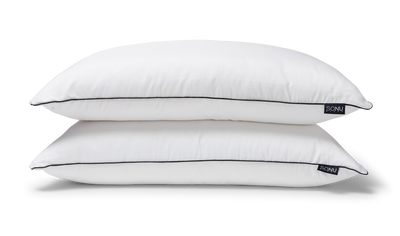 Photo of two stacked SONU Top Pillows in white with black piping