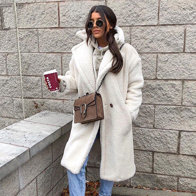 girl standing outside holding a coffee wearing a furever prague ivory faux fur teddy coat