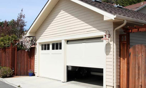 A white garage with a door half open and one closed and a dark roof