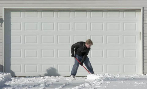 Man sweeping snow from the front of a garage