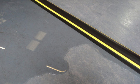 A fitted garage door threshold seal on an epoxy floor
