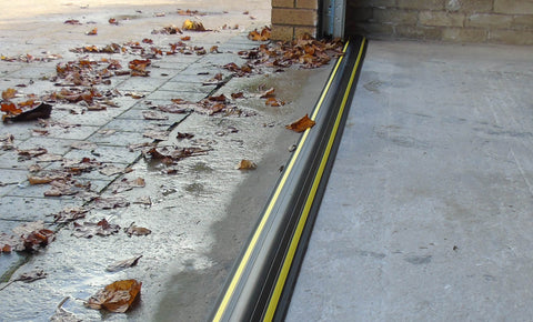 Installed garage door threshold seal protecting a garage from water and leaves