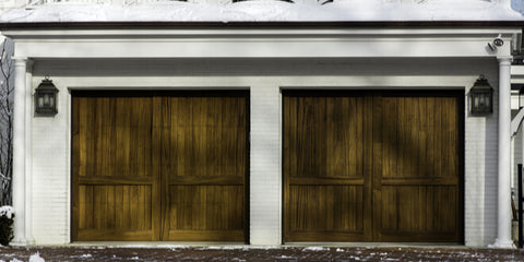 A picture showing a white garage with worn wooden doors